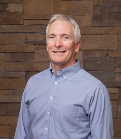 Dr. Ukena poses for his headshot with a relaxed, friendly smile and healthy looking teeth.