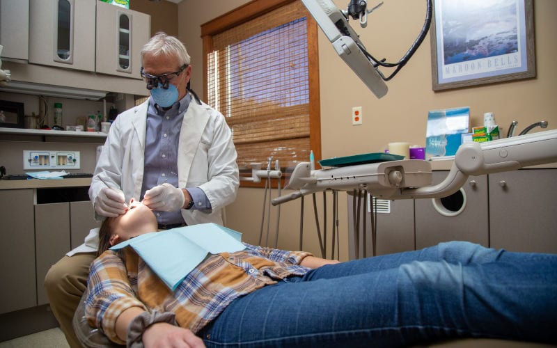 Dr. Ukena performs dental work on a patient as they rest with their mouth open during their appointment.