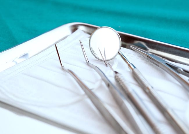 Dental tools are prepared and lay in a row on a sanitized tray, making them ready for use on a patient.