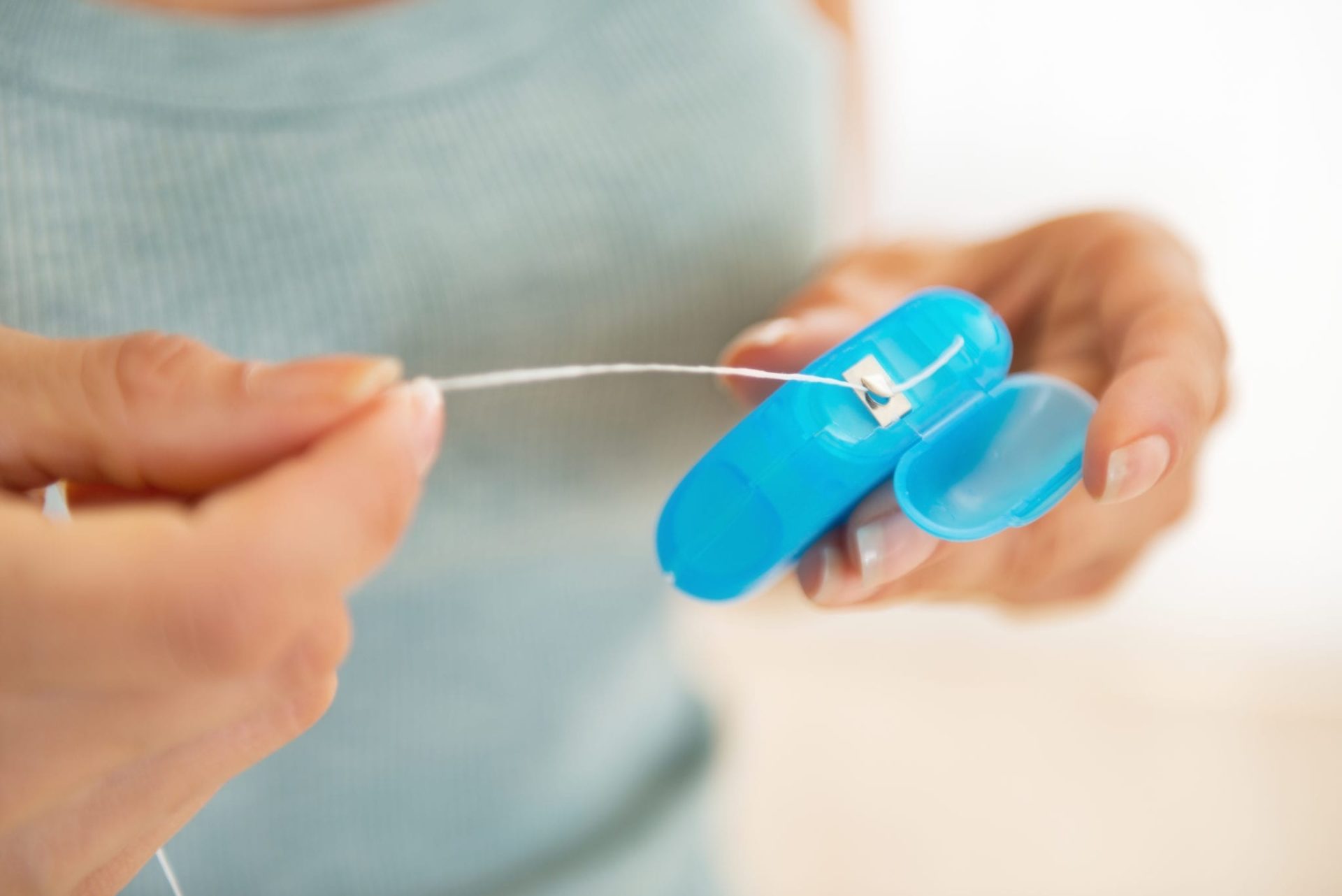 A woman holds a dispenser of dental floss.