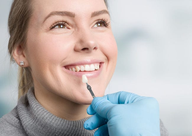 A dentist color matches a porcelain veneer to a patient's natural tooth color to ensure the best fit for the patient's smile.