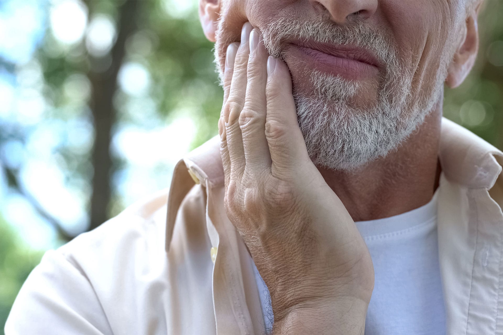 Man with a toothache touches his cheek.